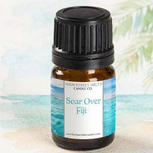 May include: A small amber glass bottle with a black cap. The label reads "Soar Over Fiji" with a beach scene. The bottle is from Main Street Melts Candle Co. and has a screw-on cap.