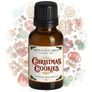 May include: A small amber glass bottle with a black ribbed cap, featuring a white label with the text Main Street Melts Candle Co. Christmas Cookies and the website address. The background displays a pattern of watercolor holiday cookies.