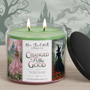May include: A two-wick candle in a clear glass jar with light green wax. The label features the text Main Street Melts CANDLE CO. CHANGED FOR GOOD, with illustrations of a figure in a pink dress and a figure in a black dress with a broom.