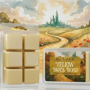 May include: Two clear plastic clamshell containers holding pale yellow wax melts. One container shows six square wax cubes, while the other displays a label with the text Main Street Melts YELLOW BRICK ROAD and a website address.