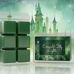 May include: A clear plastic clamshell package containing six dark green wax melt cubes. The label features a green forest and castle illustration with the text "Emerald City Lights" and "www.MainStreetMeltsCandleCo.com" printed in white.