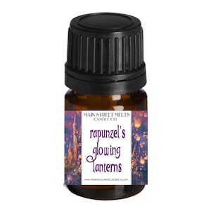 May include: A small brown glass bottle with a black lid. The label is purple and white and says "Main Street Melts Candle Co. Rapunzel's Glowing Lanterns" with a picture of a castle and lanterns.