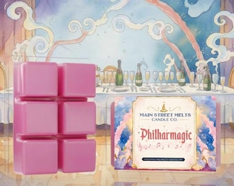 May include: A pink wax melt bar with six square segments in a clear plastic container. The label features the text Main Street Melts Candle Co. and Philharmagic, with a watercolor illustration of a banquet table and musical notes.