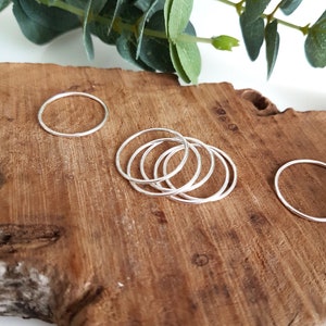 Peut inclure: Un ensemble de six bagues empilables en argent sur une surface en bois. Les bagues sont simples et délicates, et elles feraient un excellent cadeau pour un ami ou un être cher.