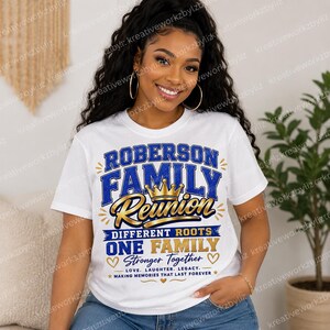 May include: White t-shirt with a blue and gold design that reads "ROBERSON FAMILY REUNION". The shirt also includes the text "DIFFERENT ROOTS ONE FAMILY STRONGER TOGETHER" with hearts and stars. A crown is in the center.