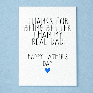 Puede incluir: Una tarjeta blanca del Día del Padre con texto negro que dice "¡GRACIAS POR SER MEJOR QUE MI VERDADERO PAPÁ!" y "FELIZ DÍA DEL PADRE" con un corazón azul. La tarjeta está sobre un fondo azul claro.