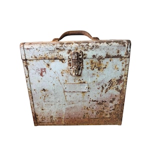 May include: A vintage, rectangular metal toolbox with a handle. The toolbox is painted a faded blue-gray color and shows signs of rust and wear. The handle is brown, and the latch is metal. The toolbox is likely used for storing tools.