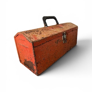 May include: A rectangular metal toolbox with a weathered orange finish and visible rust patches. The box features a black plastic handle on top and a single metal latch closure on the front side. The exterior surface shows signs of wear and age.