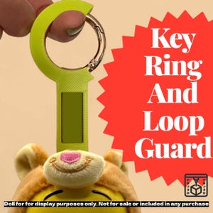 May include: A lime green key ring and loop guard with a gold-colored clasp. The text "Key Ring And Loop Guard" is displayed on a red burst. A plush toy is attached to the guard. The text "Doll for display purposes only. Not for sale or included in any purchase" is displayed.