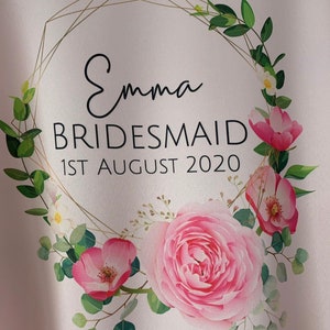 May include: A white background with a gold geometric frame and pink flowers. The text "Emma Bridesmaid 1st August 2020" is inside the frame.