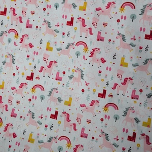 Könnte beinhalten: Weißer Stoff mit einem sich wiederholenden Muster aus rosa Einhörnern, Regenbogen, Burgen und Blumen. Die Einhörner haben rosa Mähnen und Schwänze. Die Burgen sind rot und gelb. Die Regenbogen sind mehrfarbig.