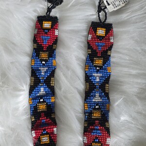 May include: Two matching beaded bracelets featuring a repeating geometric pattern in black, red, blue, yellow, and white seed beads. Each bracelet has a black tag labeled EXPRESS and a white retail price tag attached to the top loop with black thread.