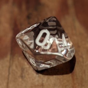 May include: A clear, transparent dice with white numbers. The dice is showing the number 4.