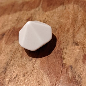 Könnte beinhalten: Ein weißer, geometrisch geformter Würfel mit abgerundeten Kanten.