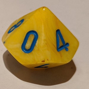 Może przedstawiać: Żółta sześcienna kostka do gry z niebieskimi liczbami. Kostka ma wzór wirowy, a liczba cztery jest widoczna na dwóch ścianach.