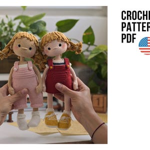 Puede incluir: Dos muñecas de ganchillo hechas a mano, una con peto rosa y otra roja, con zapatos amarillos. Las muñecas tienen el pelo rubio y están sujetas por manos. La imagen incluye el texto "CROCHET PATTERN PDF" y una bandera estadounidense.
