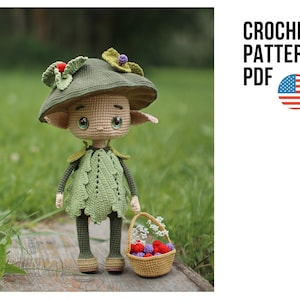 Puede incluir: Muñeca de ganchillo de una criatura parecida a un elfo con un sombrero verde y un vestido en forma de hoja, sosteniendo una cesta de bayas. La muñeca tiene ojos grandes y está de pie sobre una superficie de madera. El texto "CROCHET PATTERN PDF" se muestra con la bandera estadounidense.