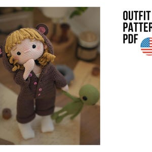May include: A handmade crochet doll wearing a brown bear outfit with a hood and pink ears. The doll has blonde hair and is holding a small green alien. The text "OUTFIT PATTERN PDF" is displayed with an American flag.