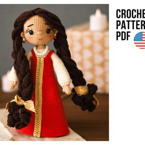 May include: A handmade crochet doll with long brown braids, wearing a red dress with gold trim and a white blouse. The doll has a tan face with delicate features and is adorned with small earrings. The image includes the text "CROCHET PATTERN PDF" with an American flag.