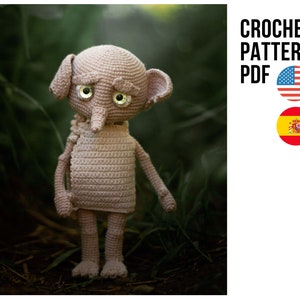 Op de afbeelding: Haakpatroon PDF voor een beige gehaakte amigurumi pop met grote ogen en een puntige neus. De pop staat op een bed van groene bladeren.