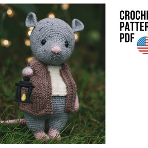 May include: Crochet pattern PDF for a gray crocheted mouse holding a small lantern. The mouse is wearing a brown cardigan and a white shirt. The pattern is available in US English.