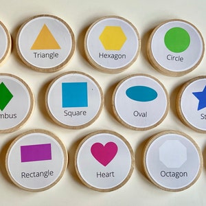 May include: Set of 12 wooden circles with different shapes and colors, including a red pentagon, yellow triangle, yellow hexagon, green circle, green rhombus, blue square, blue oval, blue star, purple rectangle, pink heart, white octagon, and gray trapezoid.