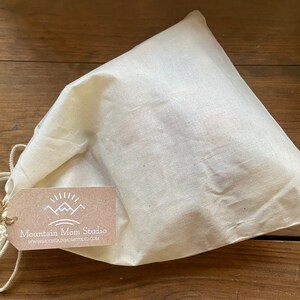 May include: A white cotton drawstring bag with a brown tag that says "Mountain Mom Studio" and "www.mountainmomstudio.com".