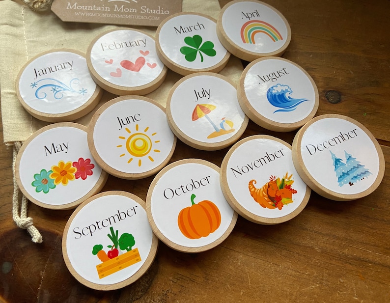 May include: Twelve wooden circles with images representing each month of the year. The circles are arranged in a semi-circle on a wooden surface. The months are January, February, March, April, May, June, July, August, September, October, November, and December.