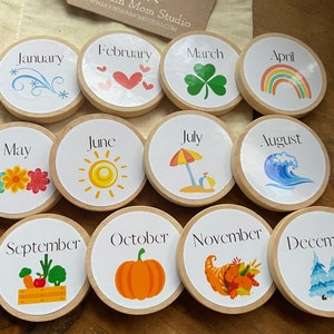 May include: Twelve wooden circles with a different month of the year and a corresponding image on each. The months are January, February, March, April, May, June, July, August, September, October, November, and December.