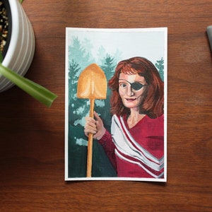 May include: A painting of a woman with red hair wearing a red and white striped shirt and an eye patch. She is holding a golden shovel in front of a green forest background.