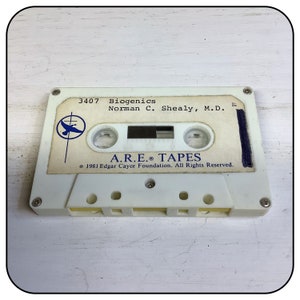 Może przedstawiać: Biała kaseta magnetofonowa z etykietą zawierającą tekst 3407 Biogenics Norman C. Shealy, M.D. oraz A.R.E. TAPES 1981 Edgar Cayce Foundation. All Rights Reserved. Po lewej stronie nadrukowano niebieskie okrągłe logo z sylwetką ptaka.
