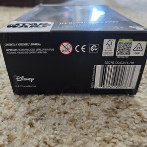 Puede incluir: Caja de juguetes negra de Star Wars con el logotipo de Disney. La caja contiene un accesorio y un diorama. La caja tiene un c&oacute;digo de barras e informaci&oacute;n de reciclaje.