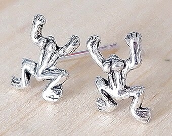 May include: A pair of silver frog stud earrings. The frogs are in a jumping pose with their legs outstretched.