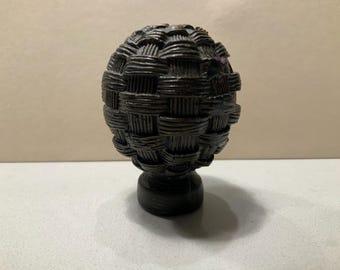 Remate de lámpara con forma de mimbre tejido y relieve, acabado en latón antiguo.