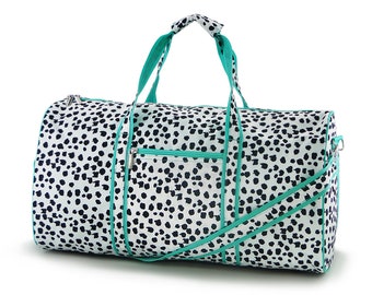 May include: A white and black dalmatian print duffel bag with teal trim and a zippered pocket on the front.