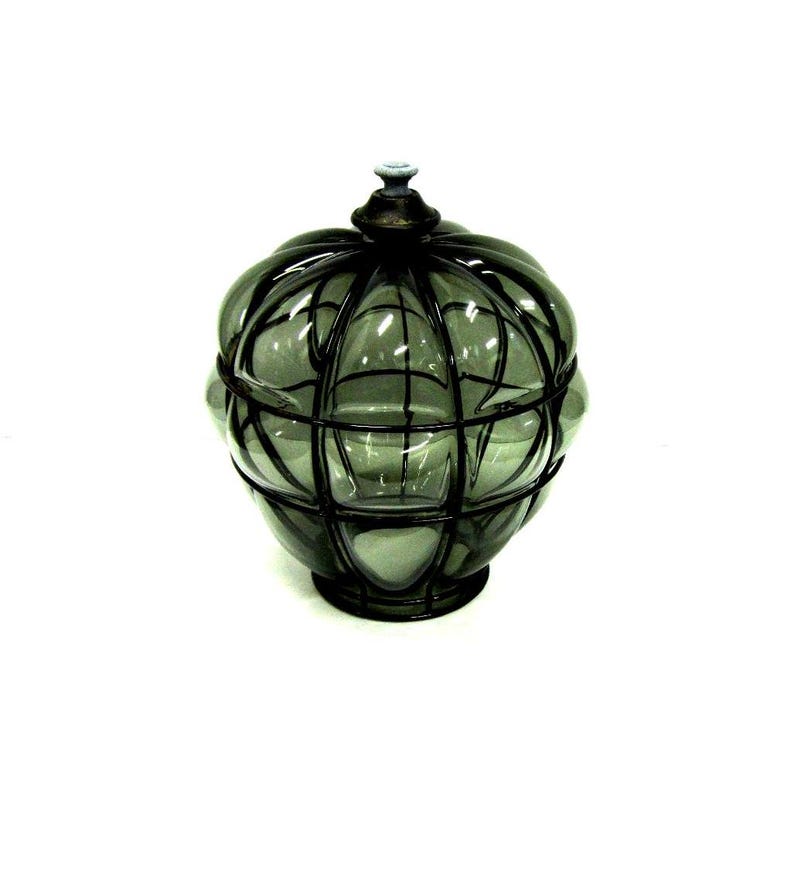 Puede incluir: Un tarro de vidrio decorativo con un dise&ntilde;o de jaula de metal oscuro. El tarro es de color verde apagado y tiene forma redonda con tapa. La jaula de metal a&ntilde;ade una est&eacute;tica vintage o antigua.