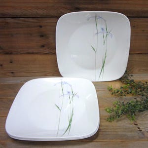 May include: A white ceramic mug with a black handle and the text "But First, Coffee" in a bold, black font. The mug is set against a neutral background, highlighting its simple design.