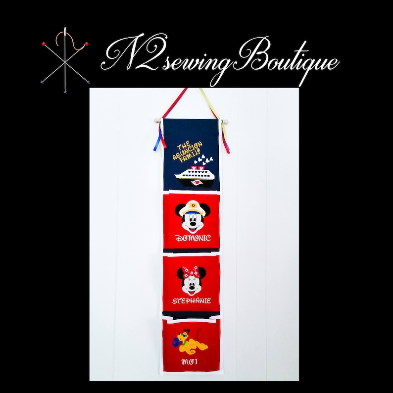 May include: A red, white, and blue fabric wall organizer with four pockets. The top pocket has a blue background with the text "The Asuncion Family" and a white cruise ship. The second pocket has a red background with a cartoon image of Mickey Mouse wearing a captain's hat and the text "Dominic". The third pocket has a red background with a cartoon image of Minnie Mouse wearing a red bow and the text "Stephanie". The bottom pocket has a red background with a cartoon image of Pluto and the text "Moi".