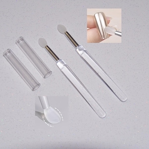 Puede incluir: Herramientas transparentes para nail art con un vástago de metal plateado y una punta de silicona blanca de forma ovalada. También se incluyen dos tubos protectores de plástico transparente. Herramientas para aplicar y manipular productos de nail art.