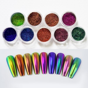 Puede incluir: Una selección de productos para manicura. Diez pequeños botes transparentes llenos de polvos de purpurina de varios colores. Debajo, diez puntas de uñas iridiscentes muestran una gama de colores.
