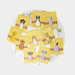 May include: A set of ten iron-on patches featuring different dog breeds. Each patch is yellow with a white border and features the text "My Pet Dog" in black. The patches are arranged on a white plate with a floral design.