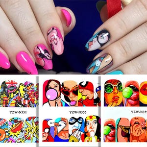 Puede incluir: Pegatinas de arte de uñas con diseños e ilustraciones de arte pop. Los diseños incluyen retratos de estilo cómic, paisajes urbanos y otros gráficos coloridos. Las uñas están pintadas con esmalte de uñas rosa brillante.
