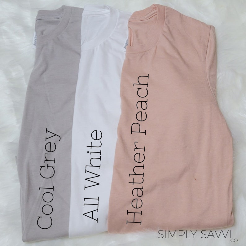 May include: Three t-shirts in different colors: cool grey, all white, and heather peach. The t-shirts are laid out flat on a white surface. The text "SIMPLY SAWVI co." is visible in the bottom right corner of the image.