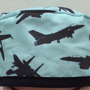 May include: A light blue scrub hat with a black trim and a repeating pattern of black fighter jets.