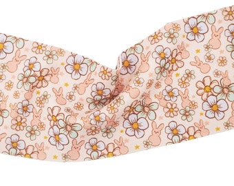 May include: A pink fabric with a repeating pattern of white flowers and pink bunnies. The fabric has a light brown background with small gold stars.