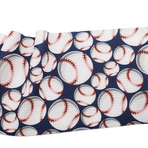 May include: A navy blue fabric with a white and red baseball pattern. The baseballs are arranged in a repeating pattern.