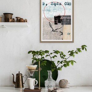 May include: A framed abstract art print with a red circle, a blue rectangle, and a black and white image of birds. The text "9, Sadu Ok" is visible in the top right corner of the print.