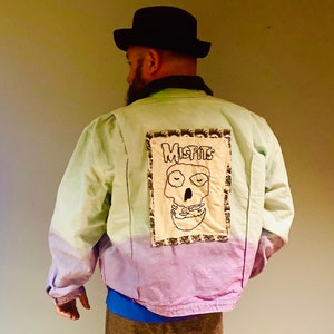 May include: A light green and purple tie-dye jacket with a black and white embroidered patch on the back that says "Misfits" with a skull graphic.