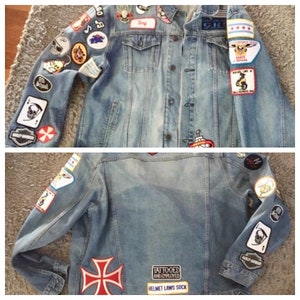 May include: A blue denim jacket with a variety of patches sewn on the front and sleeves. The patches include a skull and crossbones, a Harley Davidson logo, a cross, and a patch that says "Tattooed and Employed".