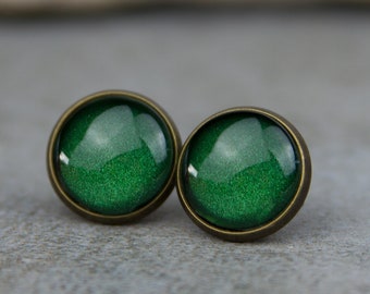May include: A pair of green glitter stud earrings with bronze settings.